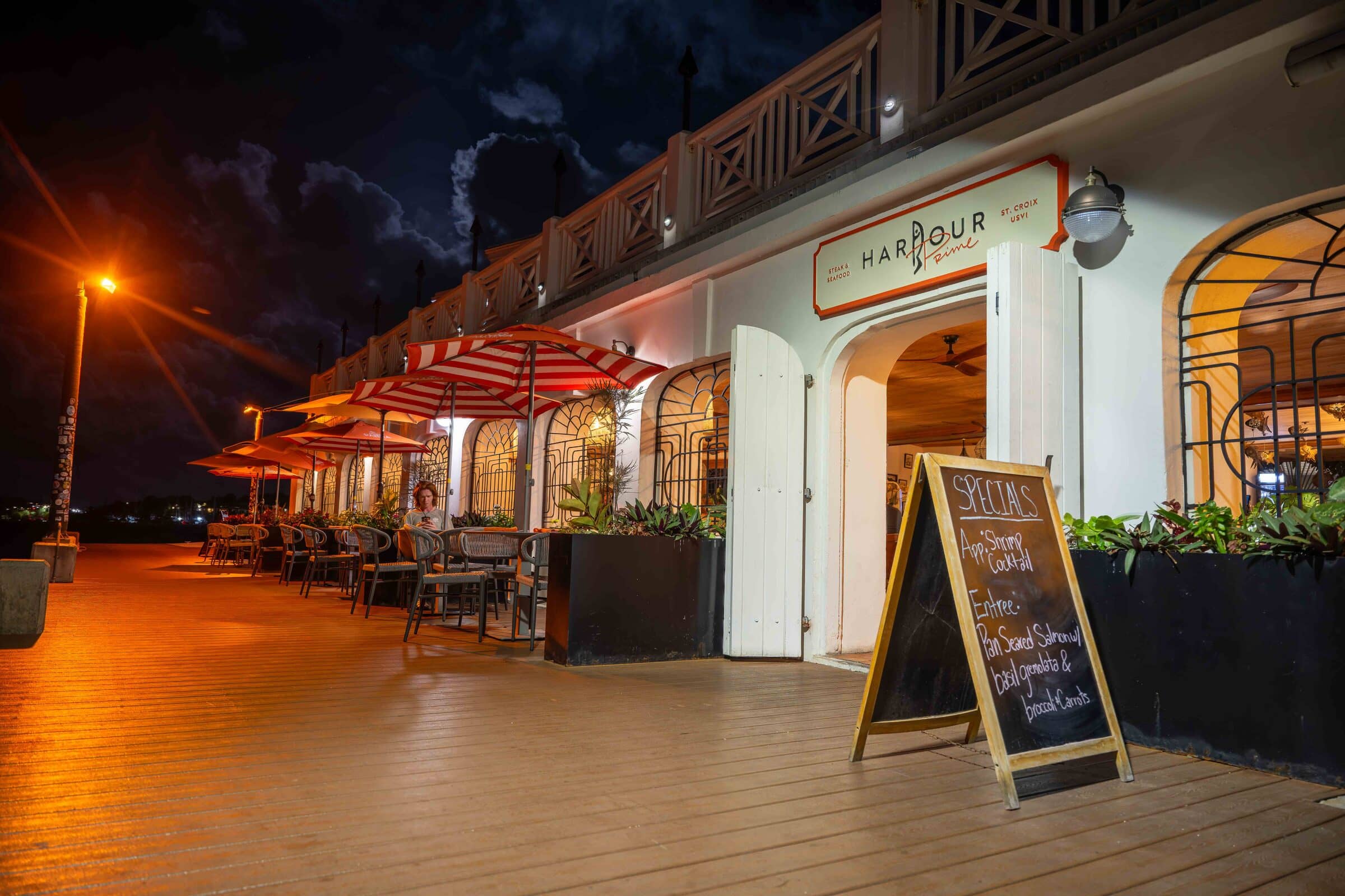 Harbour Prime's boardwalk frontage lit up at dusk on the Christiansted waterfront